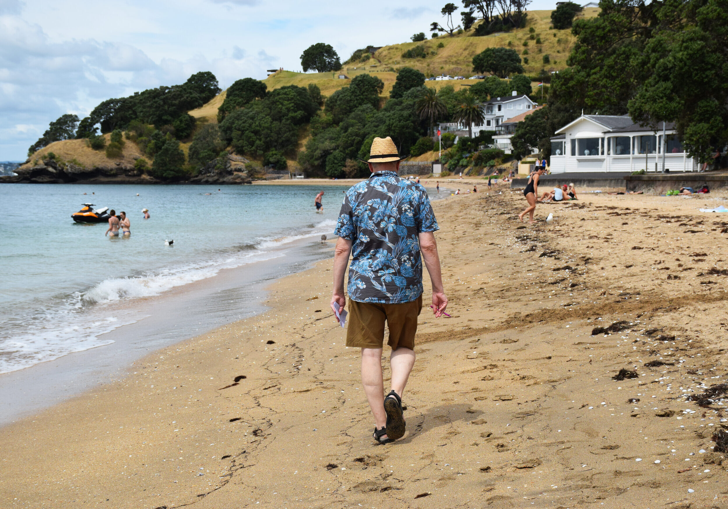 Old man walking away down the beach