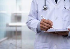 Doctor using digital tablet in hospital Doctor using electronic pen on digital tablet, reviewing medical record wrting prescription on digital document with hospital background, Electronic medical record system, health and technology, telemedicine concept